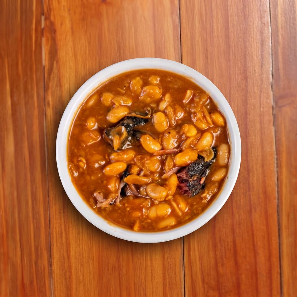 Bowl of mussels and shellfish in rich red sauce on a wooden table.