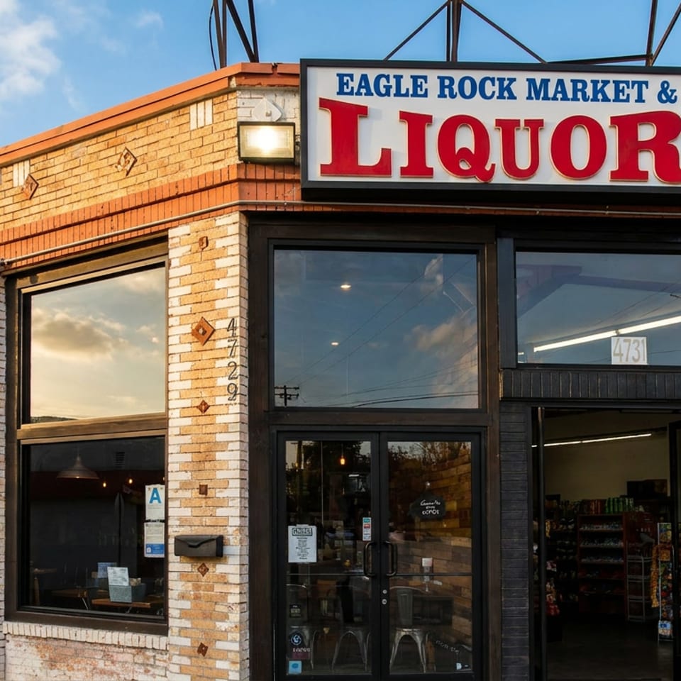 Exterior of Eagle Rock Market & Liquor, a brick building with large windows and a prominent sign.